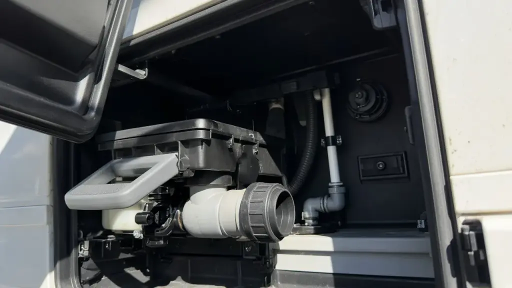 An RV black tank valve handle in the utility bay