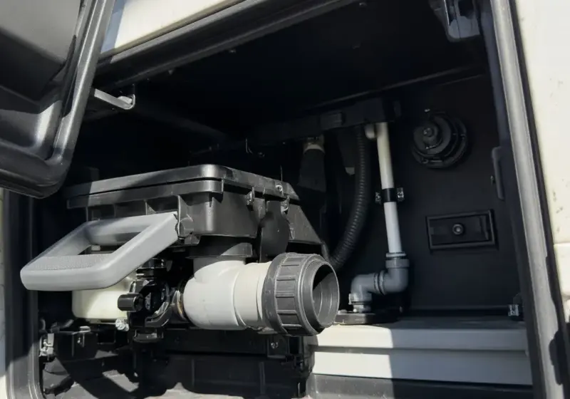 An RV black tank valve handle in the utility bay