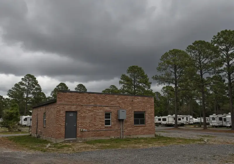 A sturdy brick building near an RV park under a stormy sky