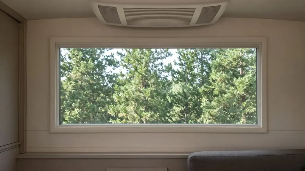 An RV window with nothing installed and a built-in ceiling AC vent above