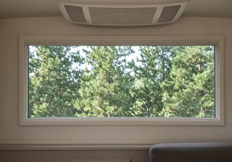 An RV window with nothing installed and a built-in ceiling AC vent above